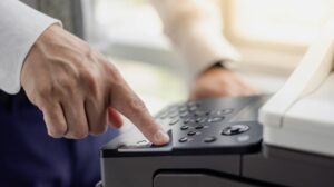 Overload office worker. Alone office worker is using a copy machine for his project at the office. Focus hand to press buttons.