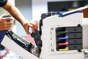 Picture of a person's hand doing maintenance to a printer