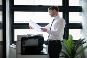 Picture of a business man working in an office. He is using the office copier